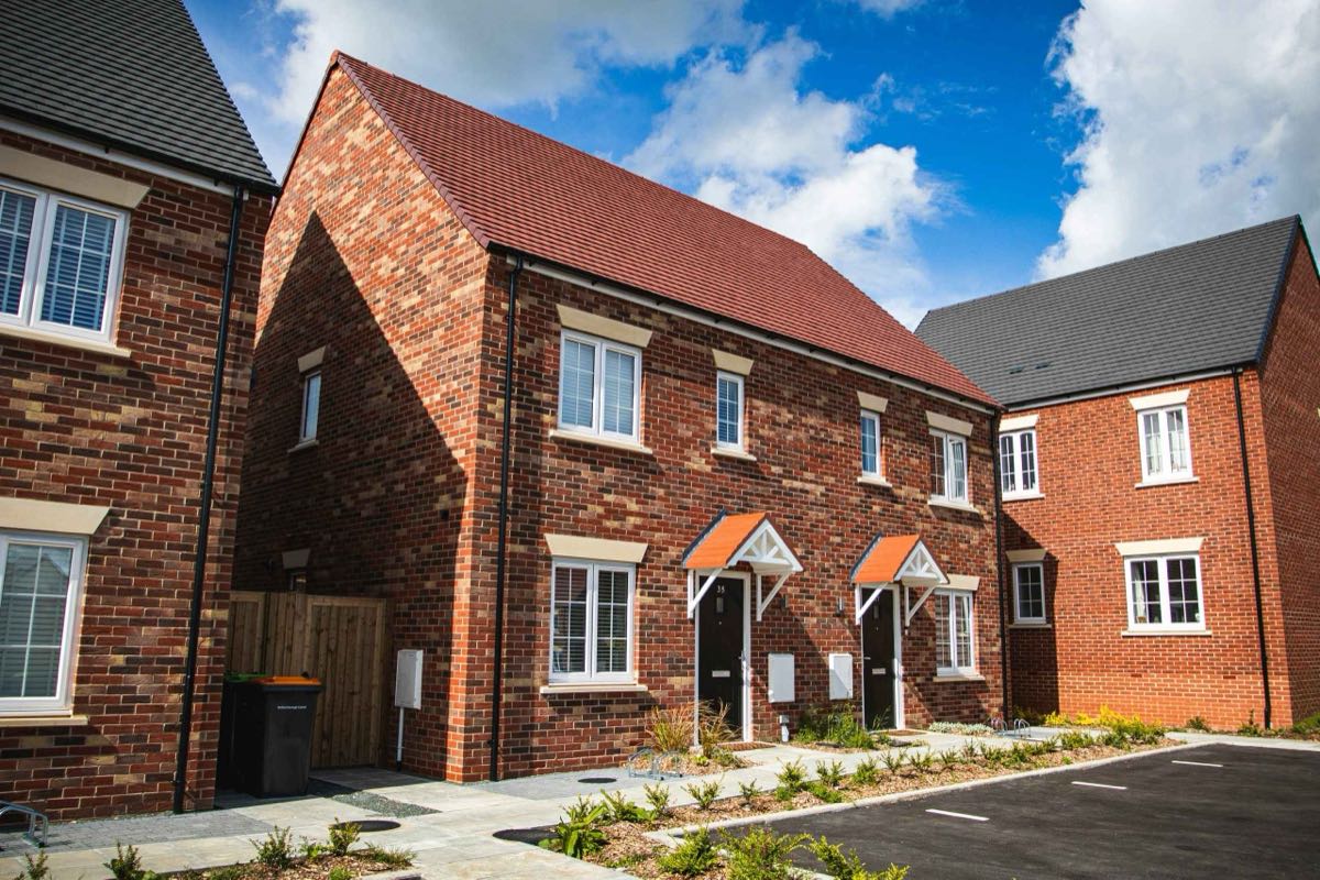 New-build brick houses on a residential development under a blue sky